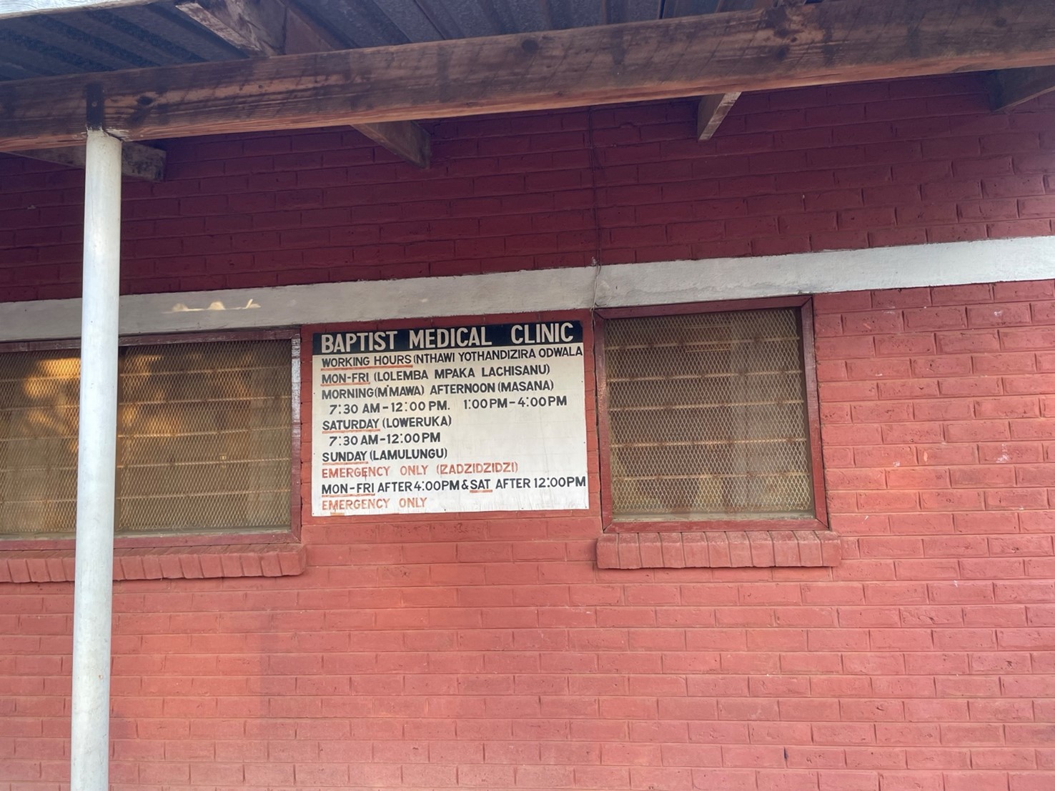 View of exterior of a medical clinic showing a signboard with opening hours